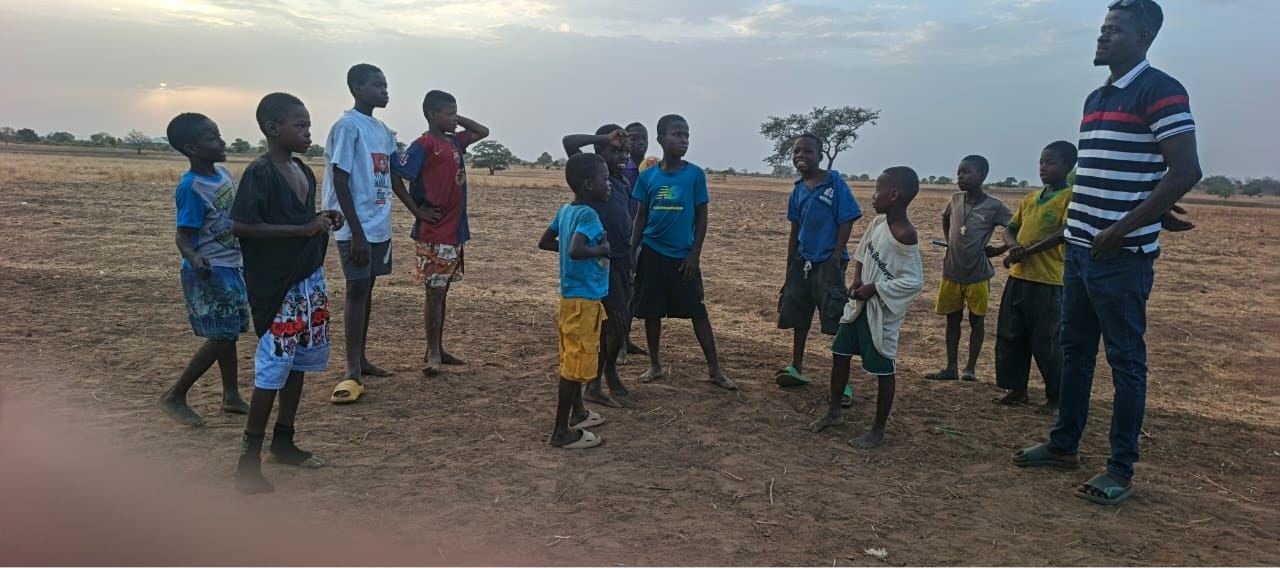 Pastor Desmond, the school's director, with JABA students on the open ground outside Gbeo